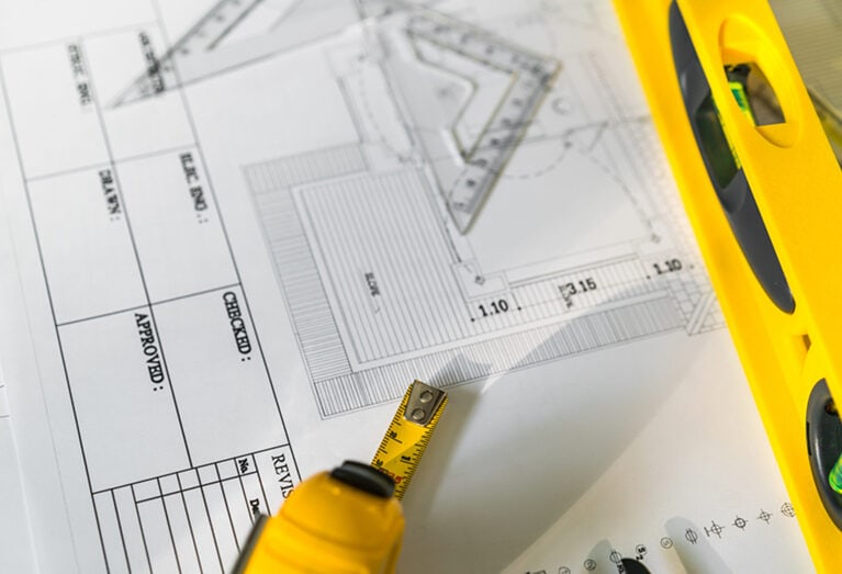 Blueprints for construction project with measuring tape and level tool, architecture layout, civil engineering, design and planning, Trager Construction LLC.